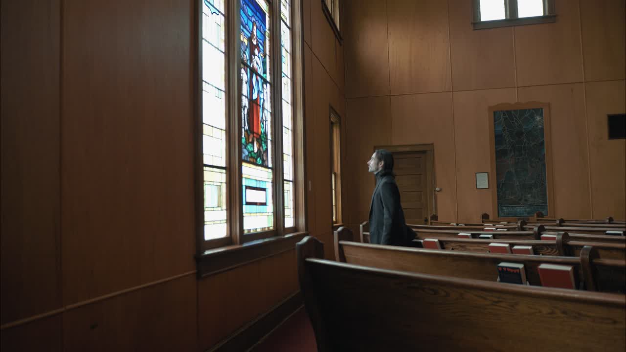 Quiet church moment as a man stands before a stained-glass depiction of Jesus with sheep, representing peace, guidance, and faith