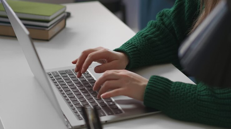 eine büroangestellte schreibt text auf der tastatur eines modernen laptops, eine nahaufnahme der hände auf dem tisch, arbeitet mit einem programm im internet, freiberuflich und teilzeit