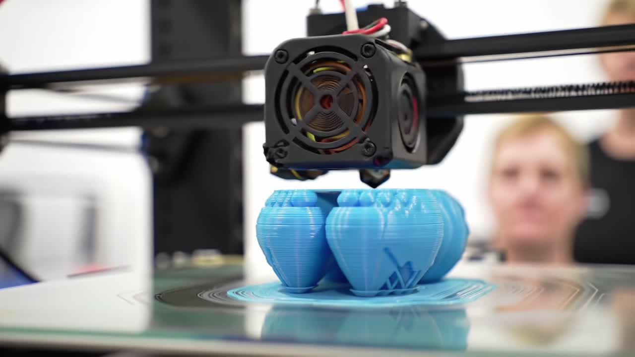 A 3D Printer in Action: Capturing the Intricate Process of Creating Blue Filament Objects with Precision and Innovation in a Modern Workshop Environment