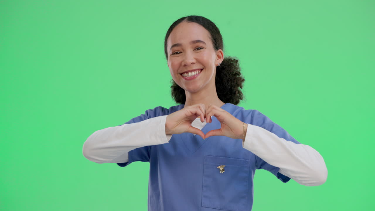 A young, smiling nurse making a heart shape with her hands