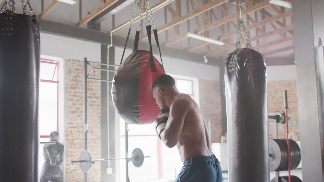 видео сзади фит афроамериканца, боксирующего в спортзале.
