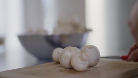 chef puts fresh mushrooms on chopping board