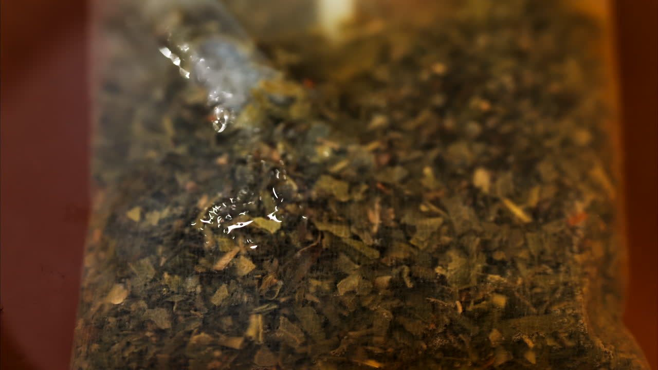 Close up of a tea bag brewing into a red cup