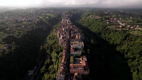 Aerial-establishing-5th-century-medieval-town-atop-narrow-ridge,-Italy