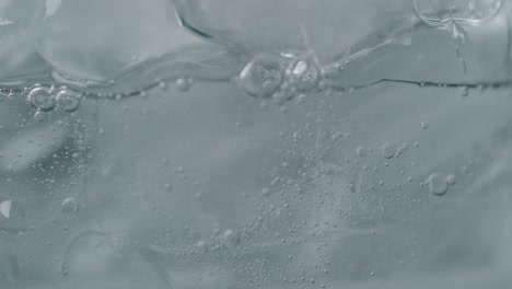 effervescent bubbles rising around ice in drink