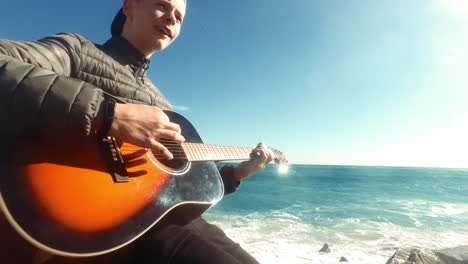 niño feliz tocando la guitarra acústica en la playa. joven músico toca la guitarra