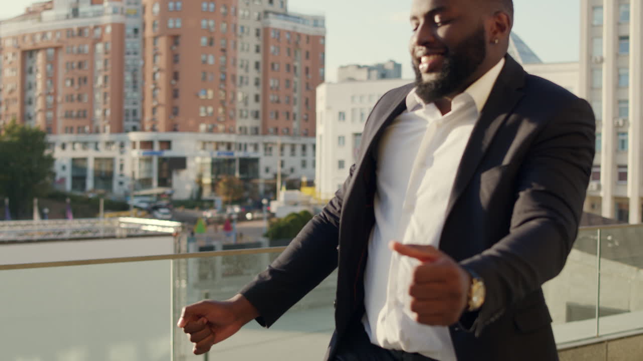 Afro man dancing after successful deal on street. Business man looking camera