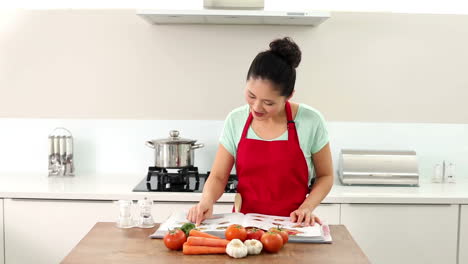 mujer sonriente mirando a través de su libro de recetas