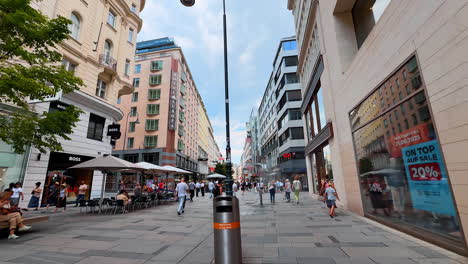 vienna, austria - june 9, 2025: tourists and locals walk by the wide pedestrian street with multiple shops. shopping in vienna, austria