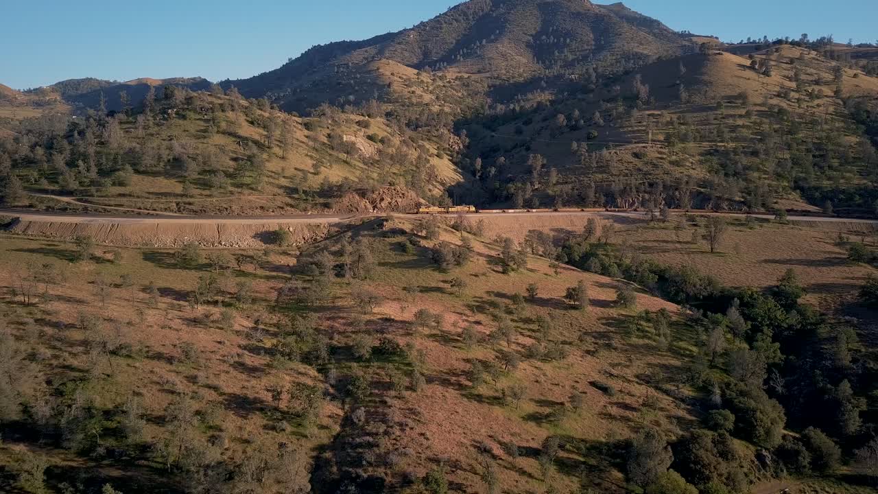 Treno in lontananza che attraversa Tehachapi, California, carrellata laterale aerea