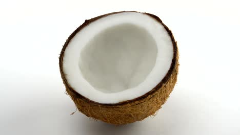 una mitad de un coco tropical maduro girando sobre un fondo blanco. frutas tropicales. en bucle