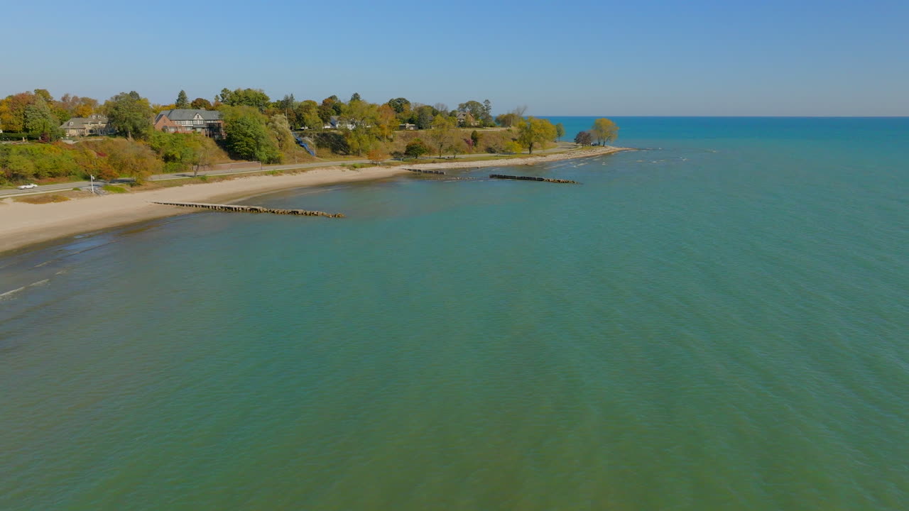 Drone aerial flying over the Lake Michigan shoreline in Sheboygan, Wisconsin with neighborhood houses, trees, and scenic waterfront views on a clear day