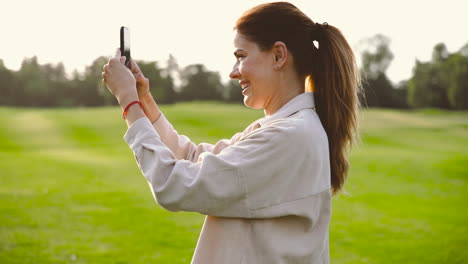 Mujer-Feliz-Tomando-Una-Foto-Con-Su-Teléfono-Móvil-En-El-Parque