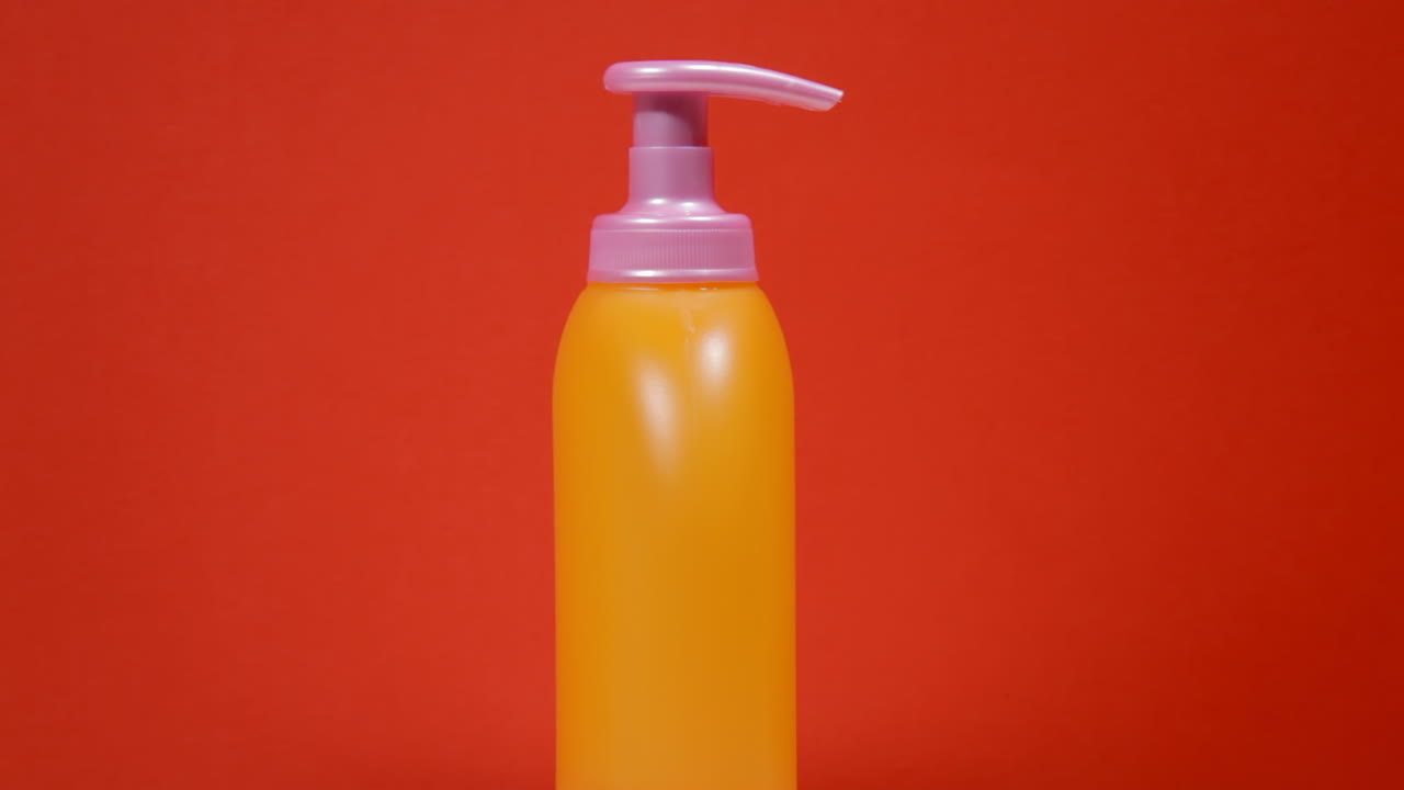 An orange soap dispenser plastic bottle on a rotating surface