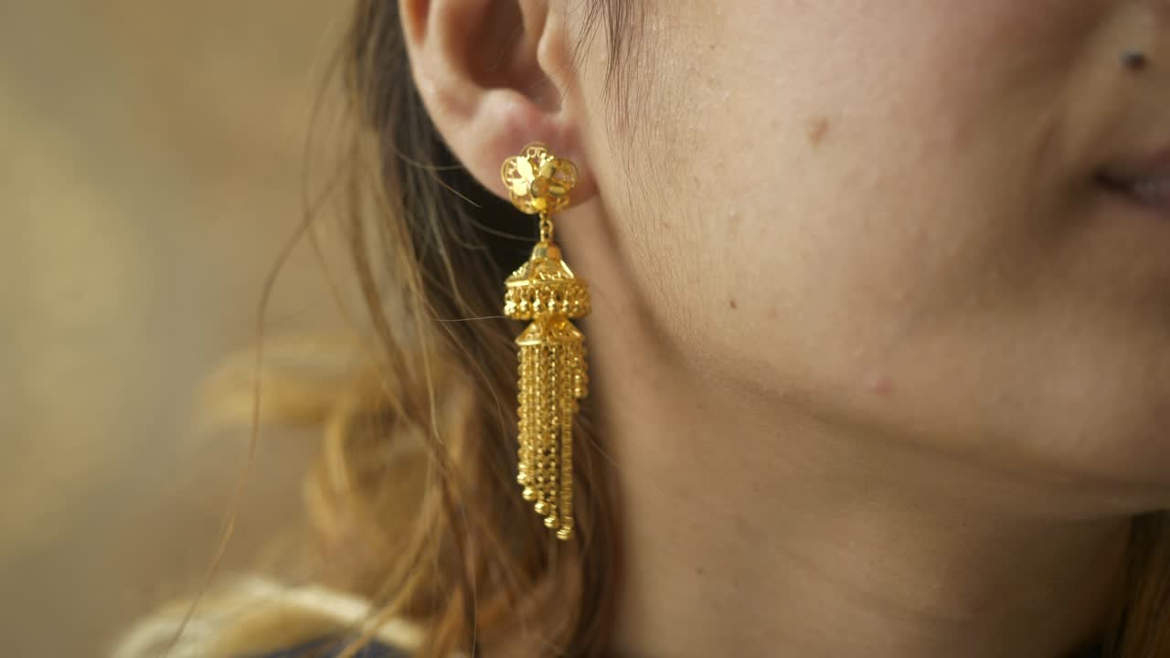 Young asian woman wearing designer 18k HUID certified gold earrings, Closeup of ear
