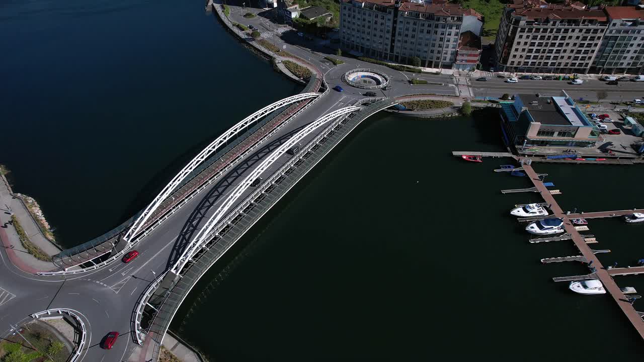 Aerial establishing shot of the Puente de las Corrientes in Galicia capturing bridge's distinctive dual white arches as it connects the north and south banks of the Lérez River near Rúa Domingo Fontán