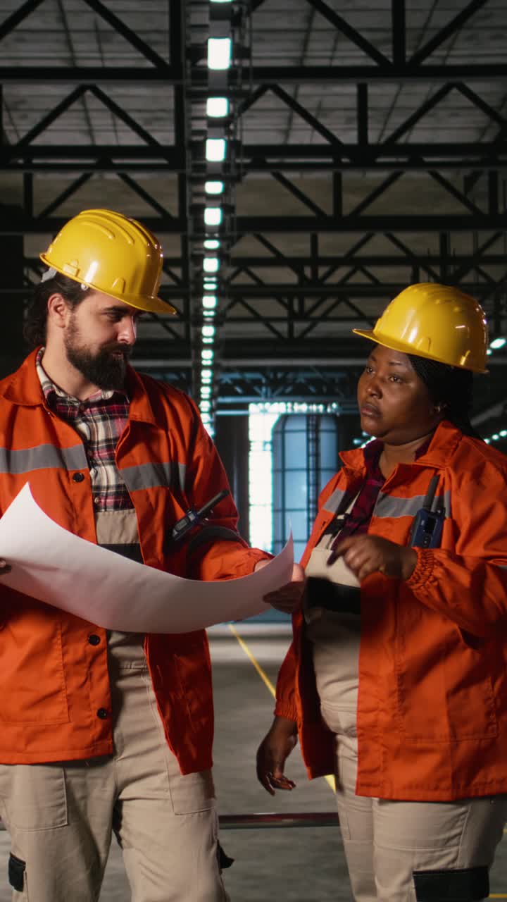 Vertical Video Multiethnic engineers examine manufacturing blueprints and circuit drawings