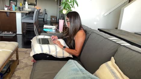 hispanic woman working at home on a laptop computer