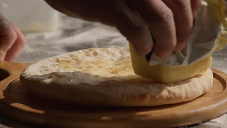 smearing butter on imeruli  khachapuri, traditional georgian food