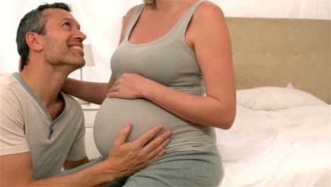 futuros padres felices en el dormitorio tocando el vientre