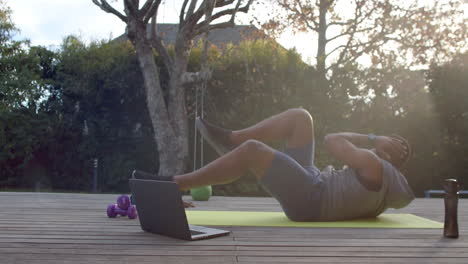 african american man exercises outdoors, following an online workout