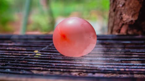 cinemagrafa de humo emitido por una parrilla de barbacoa caliente con un globo de agua colocado sobre ella.