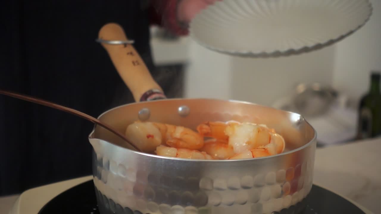 Slow-motion close-up of shrimp being lifted from a steaming pot into a plate using a ladle, highlighting texture and motion in a warm kitchen.