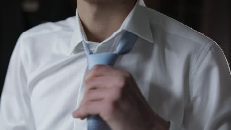 handsome groom fixes his blue bow tie. wedding morning. businessman