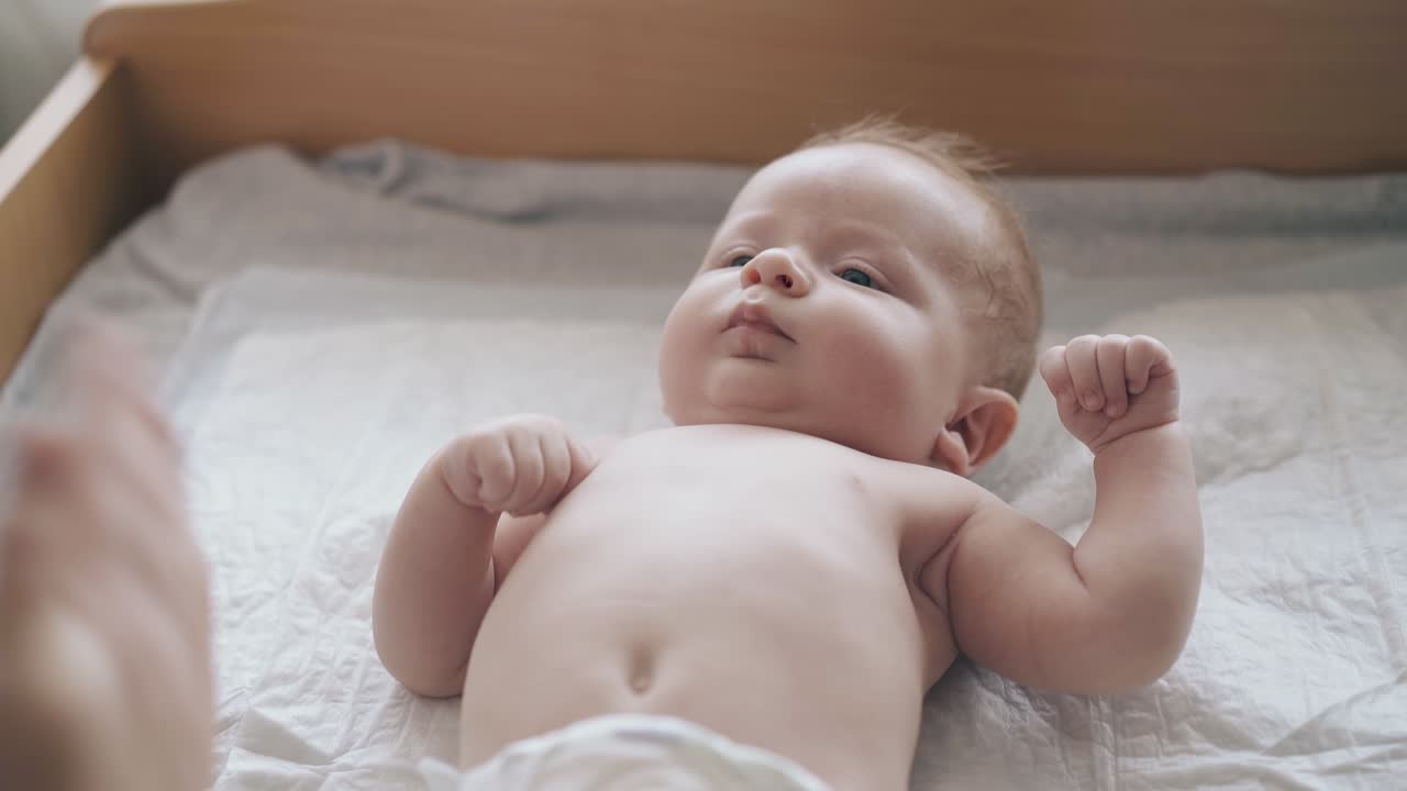 hijo recién nacido serio con cabello blanco corto y en pañal blanco