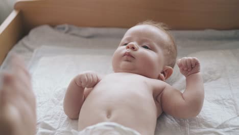 serious-newborn-son-with-short-fair-hair-and-in-white-diaper