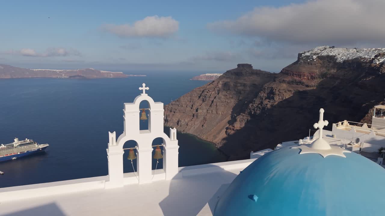 Vista de Drone da Capela de Cúpula Azul das Três Sinos em Santorini com Imerovigli na Borda do Penhasco ao Fundo, Exibindo a Caldeira e o Mar Egeu