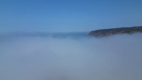 flying over the fog, with the guincho sea coast and the natural park as a backdrop,cascais,portugal