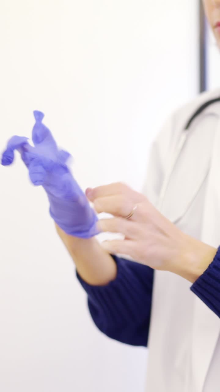 Unrecognizable female doctor putting on latex gloves in a clinic