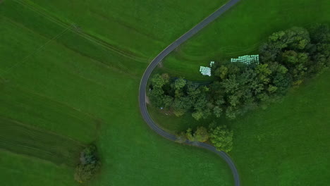 curva de carretera de asfalto en el campo de campo verde con balas de heno almacenadas