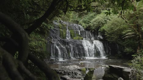 Waterfall-in-between-a-forest-on-a-sunny-day-in-Purakaunui-Falls,-Catlins,-New-Zealand