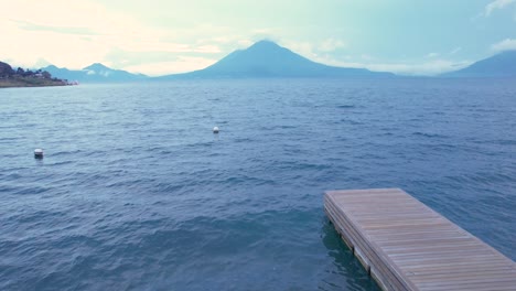 Aerial-drone-flight-over-lake-Atitlan-in-the-sunny-view-and-volcanic-mountain-on-background,-Guatemala