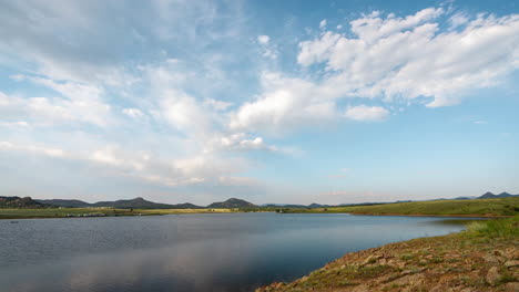 timelapse, clouds moving above green valley and alpine lake on sunny summer day