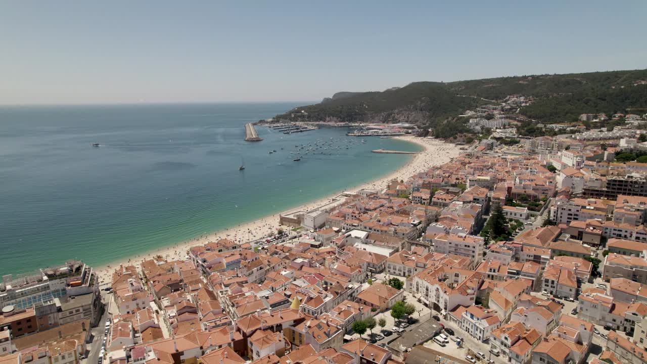 sesimbra, vista aérea de la playa y el paisaje urbano contra el puerto deportivo y las colinas.