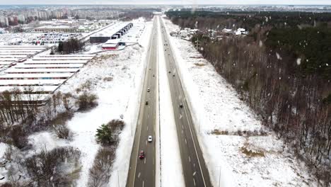 Vehicles-driving-through-A1-highway-in-winter-season-during-heavy-snowfall,-aerial-view