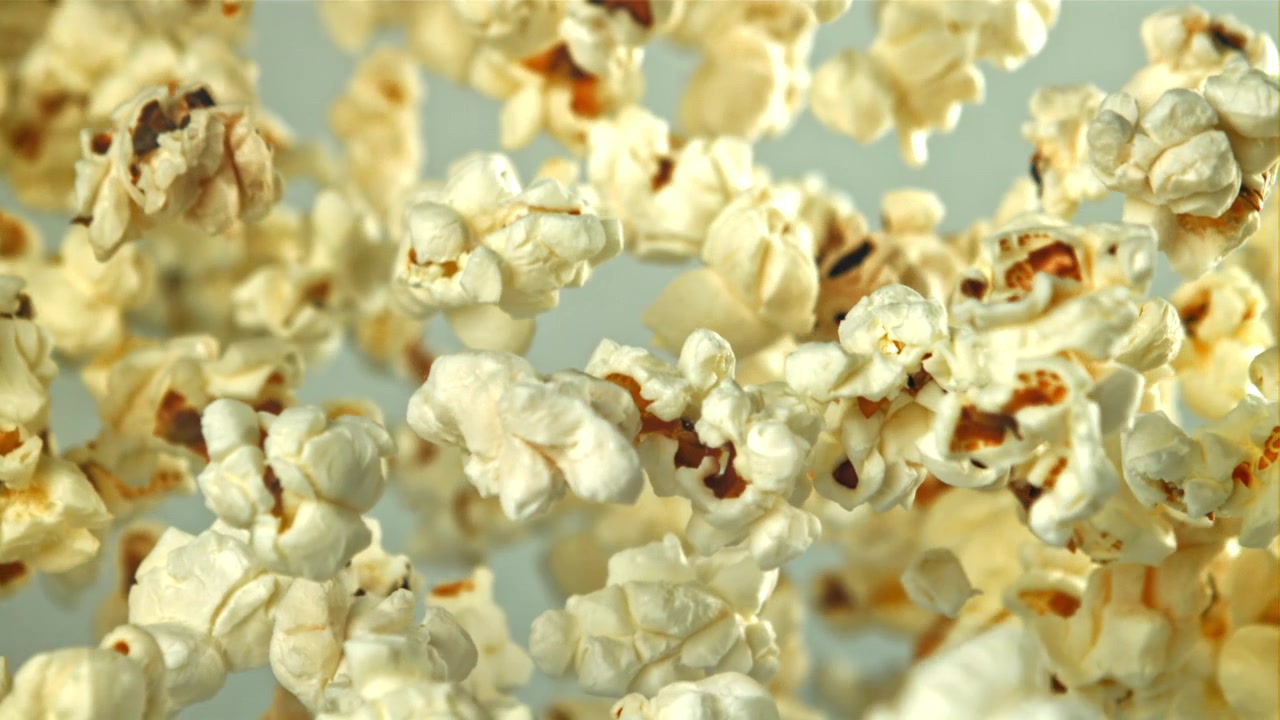 Popcorn delizioso che cadono al rallentatore su uno sfondo chiaro