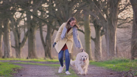 woman with prosthetic hand walking pet dog through winter or autumn countryside