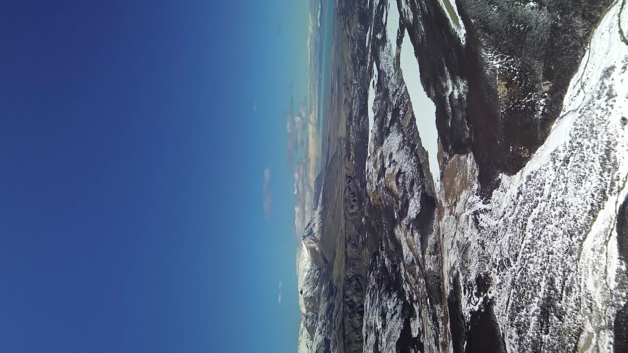 Vertical drone shot showing beautiful snowy mountain landscape against blue sky - El Chalten, Fitz Roy Mountain, Patagonia