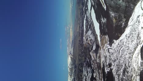 Vertical-drone-shot-showing-beautiful-snowy-mountain-landscape-against-blue-sky---El-Chalten,-Fitz-Roy-Mountain,-Patagonia