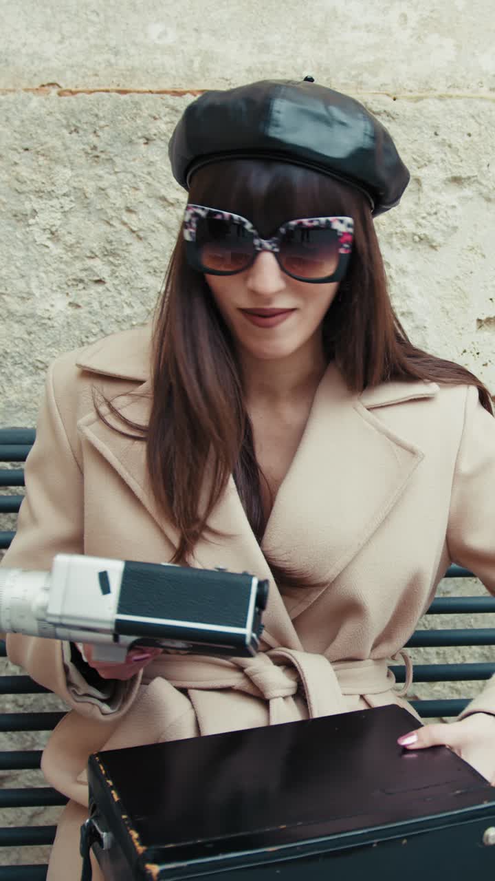 Happy Woman With A French Hat Picking Up A Vintage Camera While On A Bench