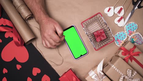 of shopping basket and phone with green screen. male hands are shopping online.