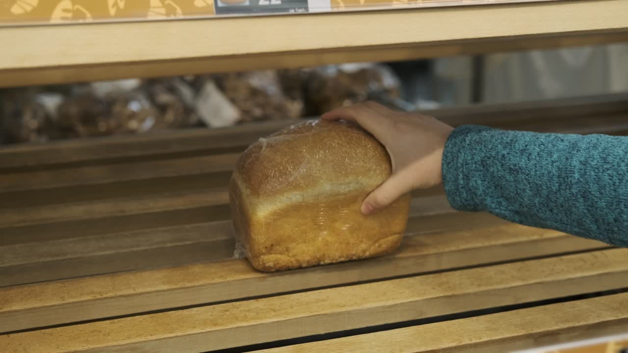 la hembra toma las últimas hojas de pan de la estantería de la tienda