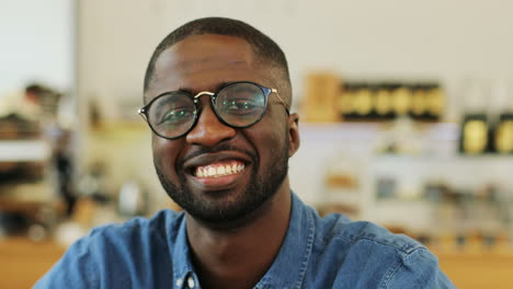 close-up view of african american man smiling at camera sitting at a table in a cafe