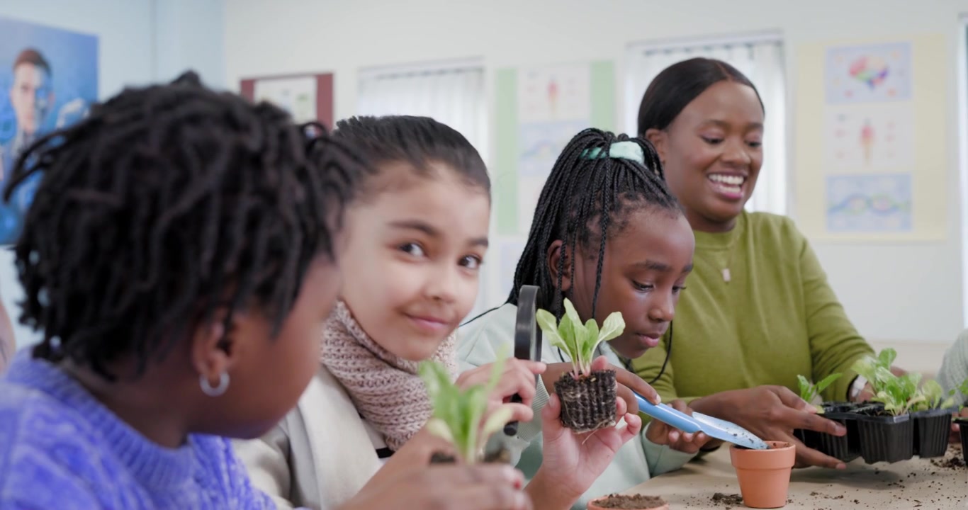 Children with teacher inspecting plants with lens at table, teacher placing tray causing potting