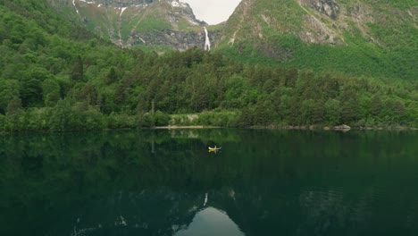 vibrant green landscape, mountains and deep lake with kayak, aerial view