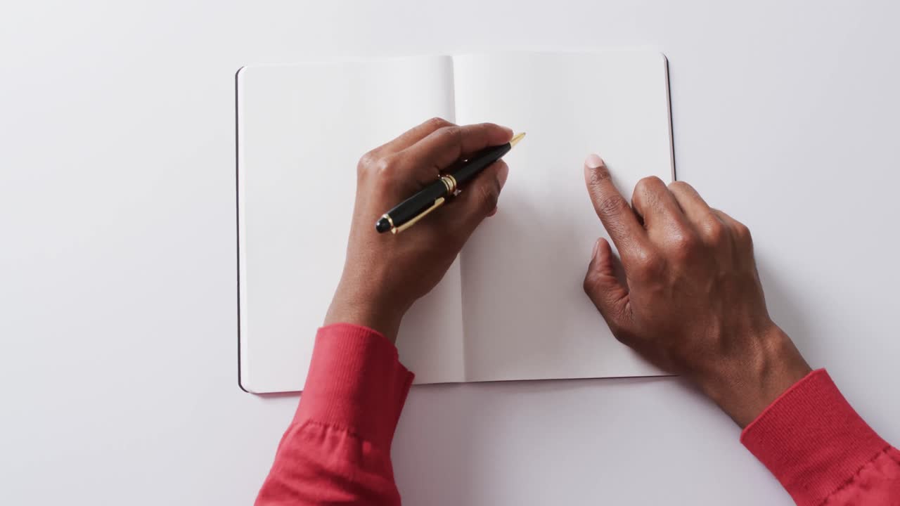 Close up of hand writing with pen on book with copy space on white background in slow motion